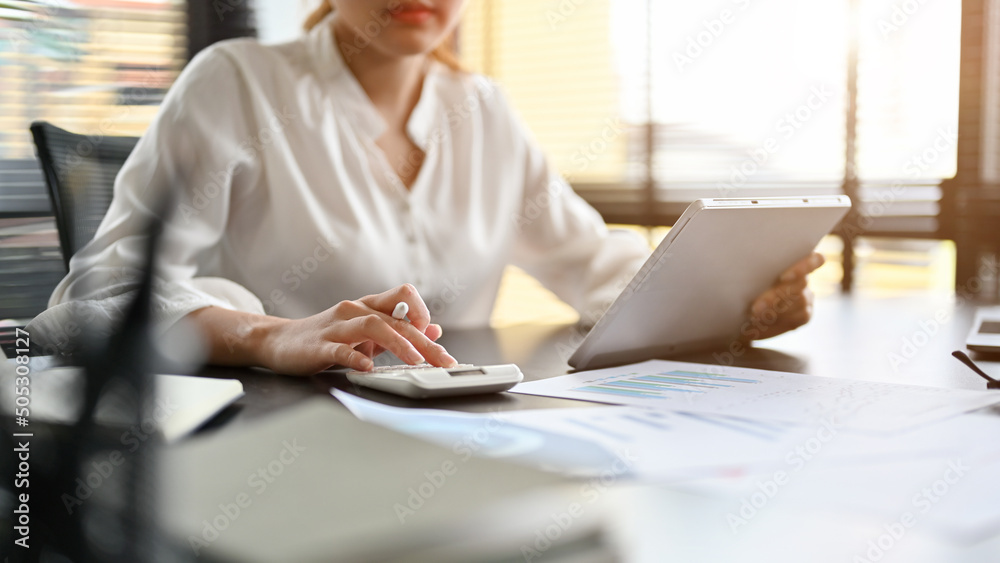 female accountant using a calculator checking and calculating a sales accounts stockpack adobe stock